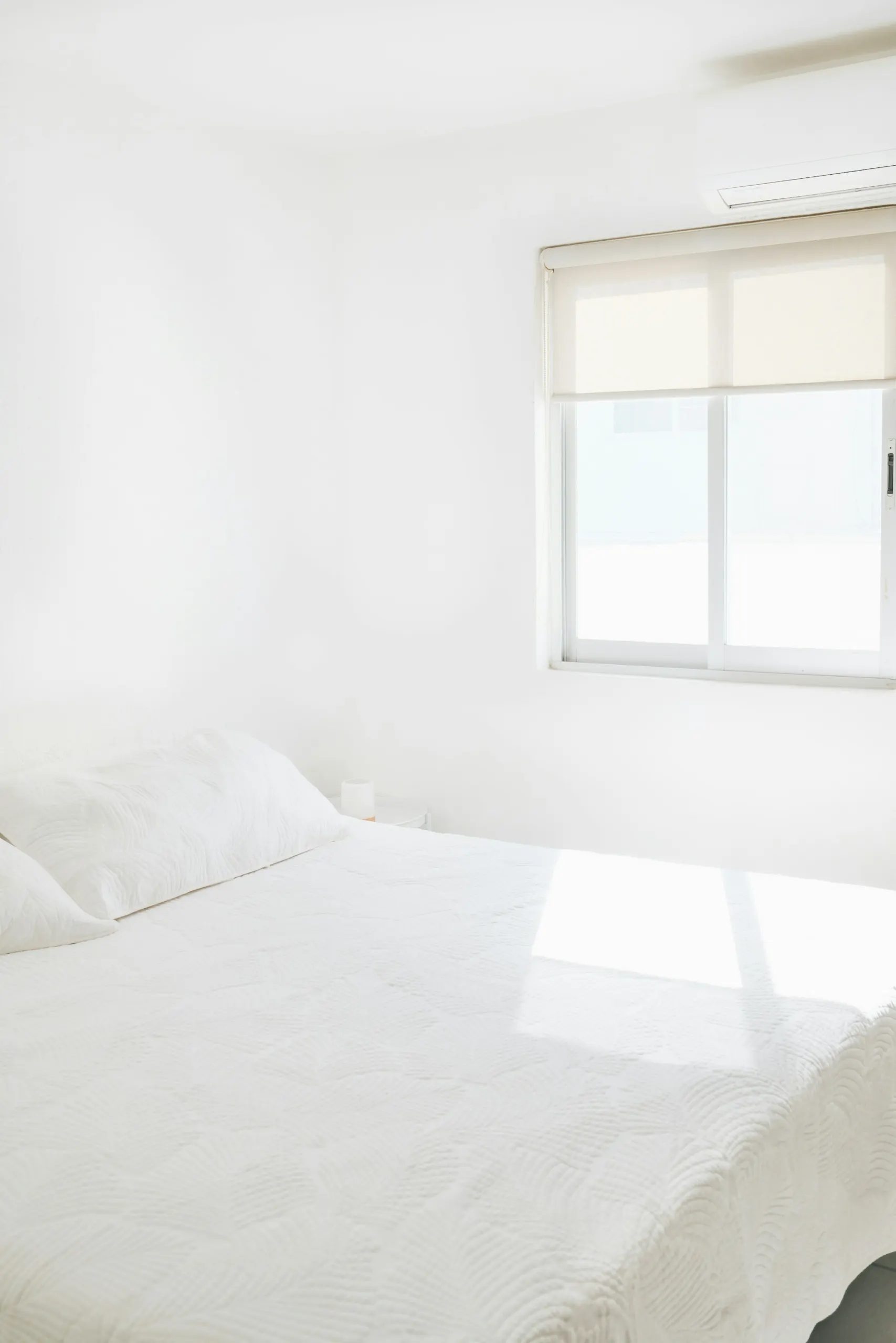 Simple whitewashed bedroom in morning light